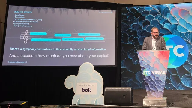 A speaker at the ITC Vegas podium beside a slide titled Maria 2017: Replayed, asking how much do you care about your capital.