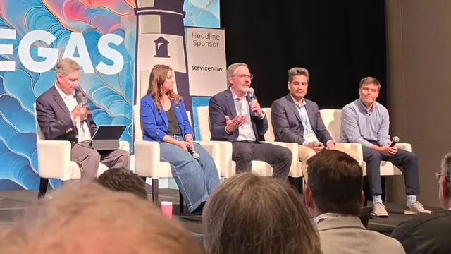 Five panelists seated on white chairs on the ITC Vegas stage, one speaking into a microphone, with ServiceNow headline sponsor signage behind them.